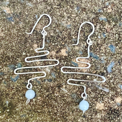 128 mz Dangle earrings are made with silvertone wire that mimics waves.  Accented with aquamarine bead at bottom.