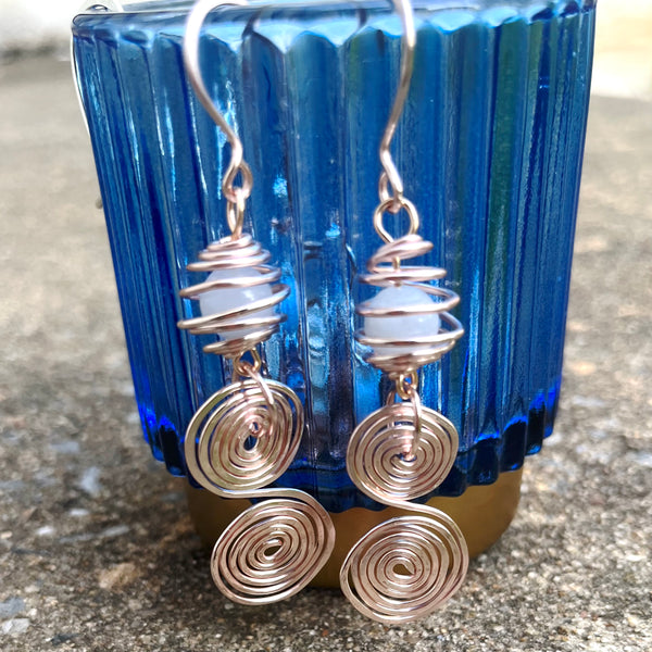 Aquamarine bead encased in gold rose wire with swirl design create these dangle earrings.
