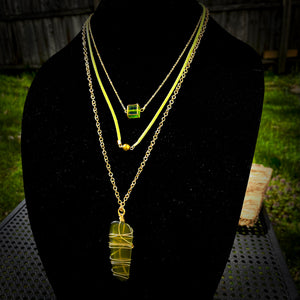 Layered necklace with two different types of gold tone chain and green leather cord.  Pendant made from glass.  