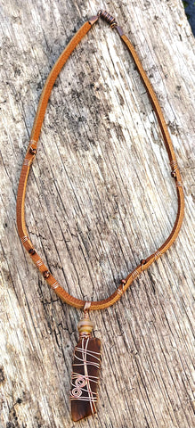 Repurposed brown glass pendant necklace with  tan leather cord.  Different brown hued seed glass beads are wire wrapped around the cord. 
