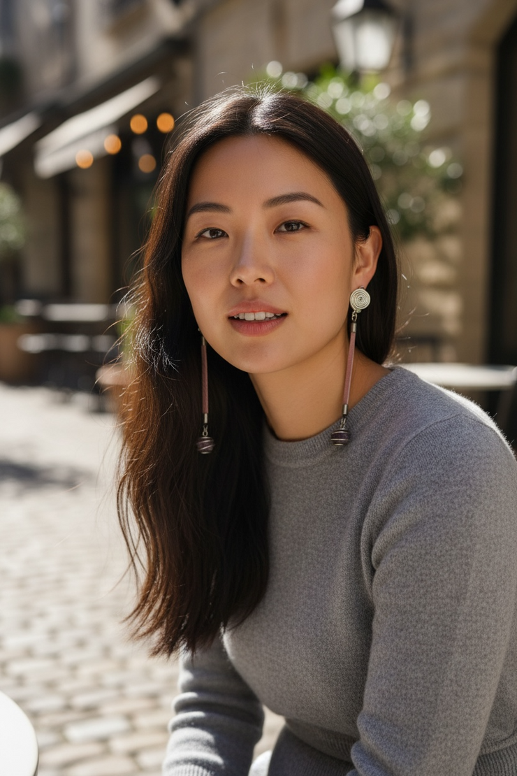 Woman with long dark hair wearing a gray sweater outdoors
