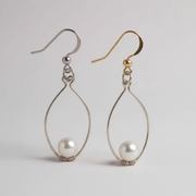 Two pairs of earrings, one silver and one gold, with teardrop-shaped wire frames and pearl beads on a light gray background.