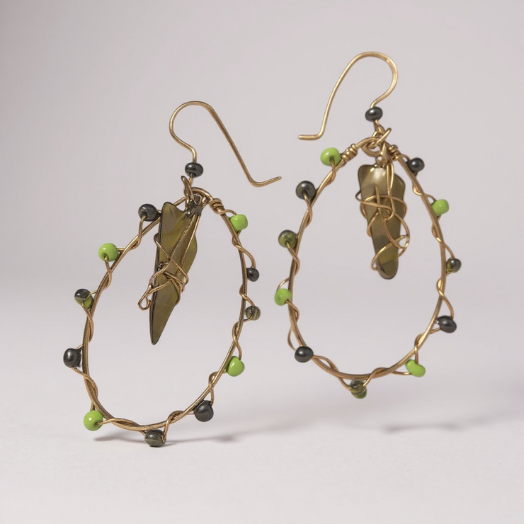 Pair of gold hoop earrings with green glass and green beads on a light gray background