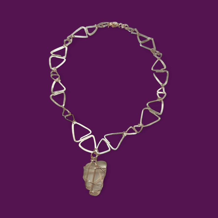 Necklace with geometric pendant on a purple background
