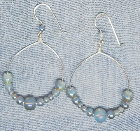 Hoop earrings with iridescent blue beads and silver tone wire.